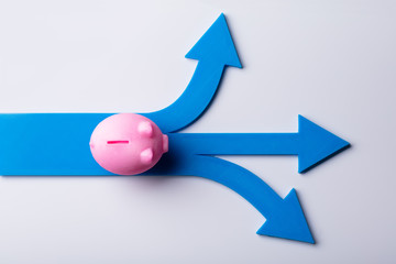 Elevated View Of Pink Piggybank And Blue Arrow Signs