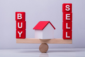 Red Cubes With Buy And Sell Text Balancing On Seesaw