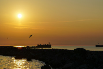 Obraz premium beautiful sunset by the breakwater port pier