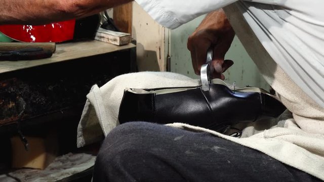 Cropped shot of a senior shoemaker working at his custom footwear shop, making new shoes. Craftsman using hammer, while working with leather. Repairing, manufacturing concept.