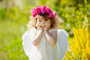 Cute little Angel girl with floral wreath, smiles and teases