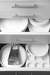 Set of kitchenware and ceramic plates in kitchen drawers