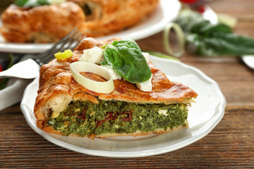 Piece of tasty pie with spinach on plate