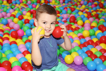 Cute boy playing among plastic balls