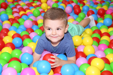 Cute boy playing among plastic balls