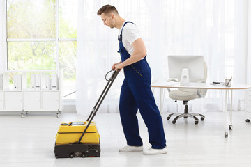 Male worker with floor cleaning machine indoors