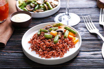 Plate with delicious brown rice and vegetables on dinner table