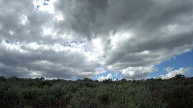 Time lapse of thick clouds rolling over the landscape and sagebrush in the Idaho desert.