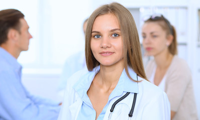 Happy doctor woman  with medical staff at the background in hospital office