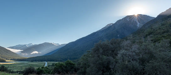 View up the Eglinton Valley towards the mountains in the early morning. Starburst of the sun...