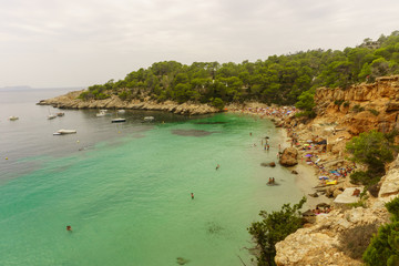 Benirras beach, Ibiza, Spain - 27 August, 2017: Young people jumping inside ocean in summer excursion day - Vacation, youth and fun concept - Soft focus on left man - Fisheye lens distortion