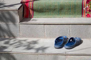 Sliders on the stairs/Blue sliders on steps of a house with open door, curtain lace and green-red footcloth