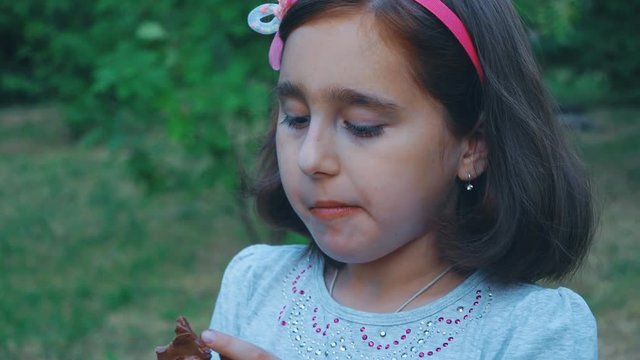little girl chewing chocolate, close-up, eating with closed mouth