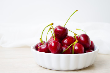 Cherries in white bowl. Cherry on white background. - healthy eating and food concept
