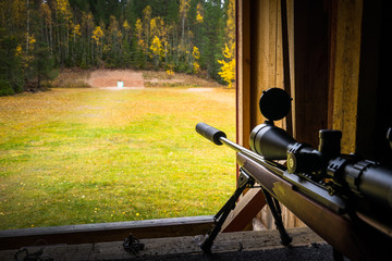 Sniper rifle with silencer and scope at shooting range  - obrazy, fototapety, plakaty
