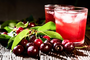 Fresh cherries and ice cherry fruit drink on wood