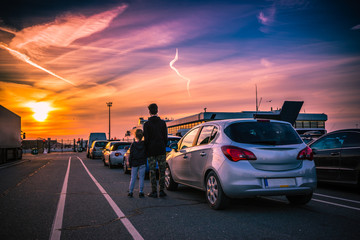 Sister and brother watching sunset while waiting to board ferry at Dunkirk port, France