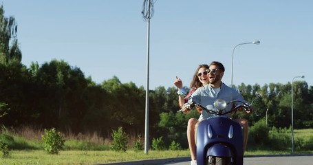 Caucasian young joyful couple in love riding on the motorcycle out of town and laughing. Summer day. Outdoors.