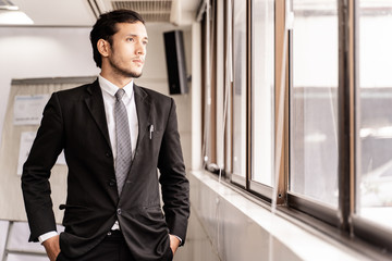 Portrait of handsome businessman standing near window in office.