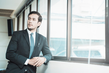 Portrait of handsome businessman standing near window in office.