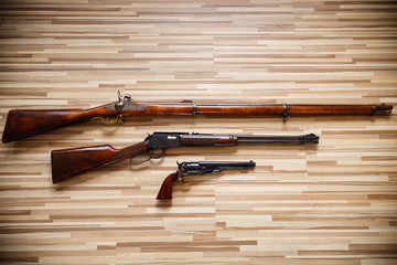 Classic American weapons on wooden background: Civil war rifle, Wild West rifle and revolver