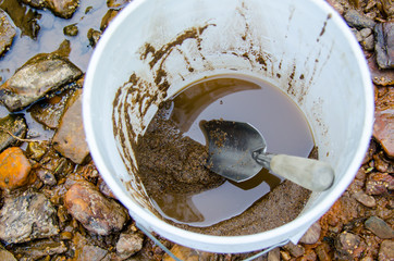 Bucket and shovel with mineral rich soil ready to classify and pan for gold and gemstones. Fun and adventure in this outdoor recreational activity of gold panning and gemstone prospecting.