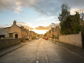 A road leads to a quiet residential neighbourhood area with traditional British style houses during...