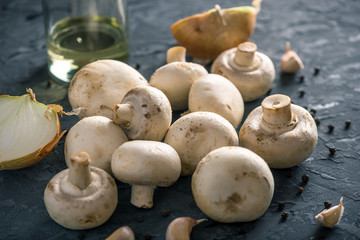 Fresh white Champions, spices and ingredients on the dark kitchen table. Concept of cooking mushroom dishes
