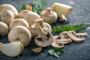 Fresh Champions, green dill and ingredients on the dark kitchen table. Concept of cooking mushroom dishes. Close up