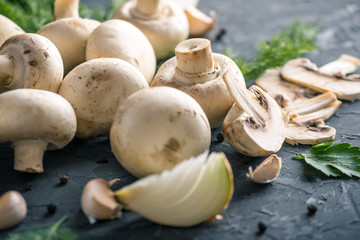 White Champions, green dill and ingredients on the dark kitchen table. Concept of cooking mushroom dishes. Close up