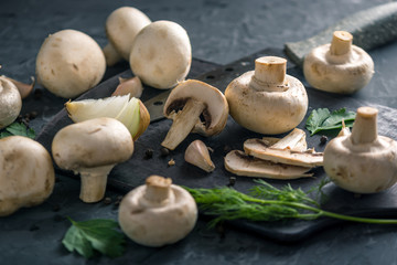 White champignons cut in half with a knife and the ingredients. Concept of cooking mushroom dishes. Close up