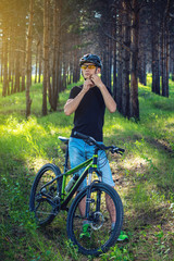 Cyclist is wearing a sports helmet on his head in the background of green nature. Concept of protection during Cycling