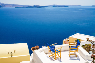 Fototapeta premium Two blue chairs at sunny summer day in Santorini - holiday concept, Cyclades. Greece 