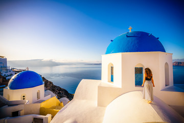 Fototapeta na wymiar Female tourist near famous blue domes of Santorini island in Grece