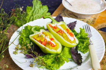 Green raw bell peppers stuffed with quinoa, bulgur, tomato, basil leaves and other vegetables with oil and rock salt for lunch or dinner. Vegan vegetarian healthy food.