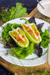 Green raw bell peppers stuffed with quinoa, bulgur, tomato, basil leaves and other vegetables with oil and rock salt for lunch or dinner. Vegan vegetarian healthy food.