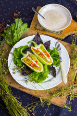 Green raw bell peppers stuffed with quinoa, bulgur, tomato, basil leaves and other vegetables with oil and rock salt for lunch or dinner. Vegan vegetarian healthy food.