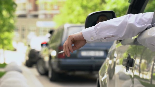 Man smoking in auto, dumping cigarette ash on street, stuck in traffic jam