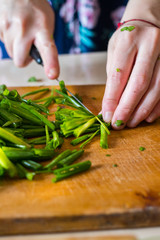 Woman hands cuts fresh herbs on wooden board preparing salad or lunch and dinner.  Raw vegan vegetarian healthy food. 