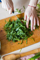 Woman hands cuts fresh herbs on wooden board preparing salad or lunch and dinner.  Raw vegan vegetarian healthy food. 