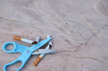 Closeup of cigarettes with scissors on marble table, symbol of stop smoking.