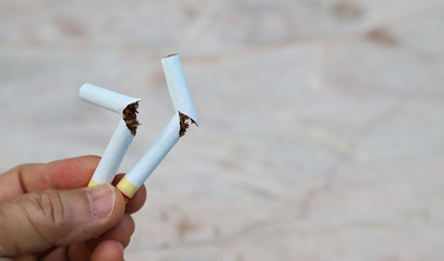  Closeup of two broken cigarettes in woman's hand, symbol of stop smoking.