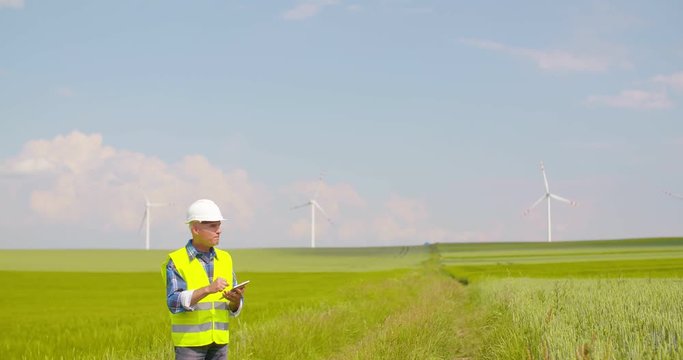 Engineer using digital tablet on Wind Turbine Farm