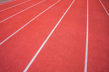 Fototapeta premium White lines of stadium and texture of running racetrack red rubber racetracks in outdoor stadium are 8 track and green grass field,empty athletics stadium with track.