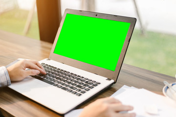 Close-up of businessman working with laptop with blank green  screen,smart phone and document on in coffee shop like the background.