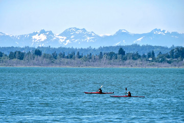 Sea kayaks in water. Kayaking in Pacific Ocean with scenic view of snow capped mountains in Olympic Peninsula. Seattle. Washington State. United States of America.