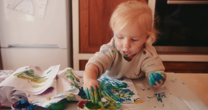Little girl with dirty hands and face finger painting