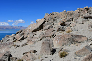 China. Great lakes of Tibet. Stones with mantras on the store of Lake Teri Tashi Namtso in sunny...