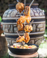Fototapeta premium Chicken meat strung on sharp metal pins of a special device for cooking in tandoor.