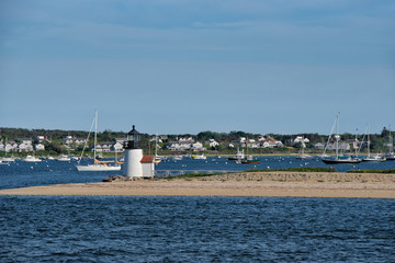 Brant Point lighthouse juts out into the harbor of Nantucket Island on a sunny, summer day